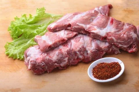 Raw Ribs on a rustic cutting board with salt, pepper and grinder for spices Stock Photos