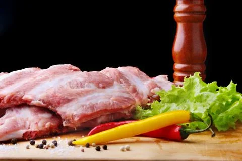 Raw Ribs on a rustic cutting board with salt, pepper and grinder for spices Stock Photos