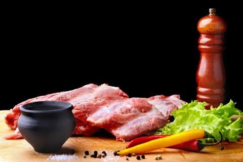 Raw Ribs on a rustic cutting board with salt, pepper and grinder for spices Stock Photos