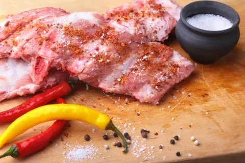 Raw Ribs on a rustic cutting board with salt, pepper and grinder for spices Stock Photos