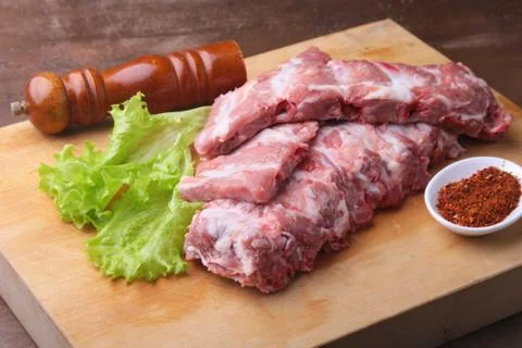 Raw Ribs on a rustic cutting board with salt, pepper and grinder for spices Stock Photos