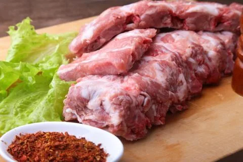 Raw Ribs on a rustic cutting board with salt, pepper and grinder for spices Stock Photos