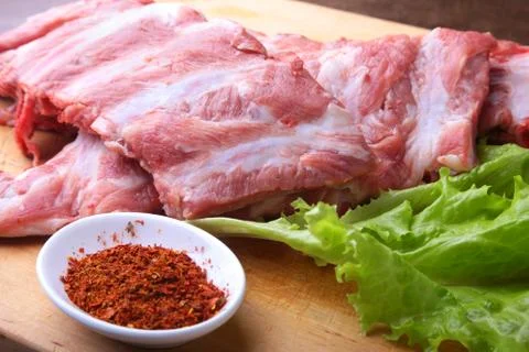Raw Ribs on a rustic cutting board with salt, pepper and grinder for spices Stock Photos