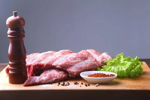 Raw Ribs on a rustic cutting board with salt, pepper and grinder for spices Stock Photos
