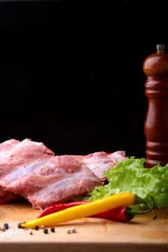Raw Ribs on a rustic cutting board with salt, pepper and grinder for spices Stock Photos