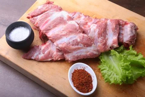 Raw Ribs on a rustic cutting board with salt, pepper and grinder for spices Stock Photos