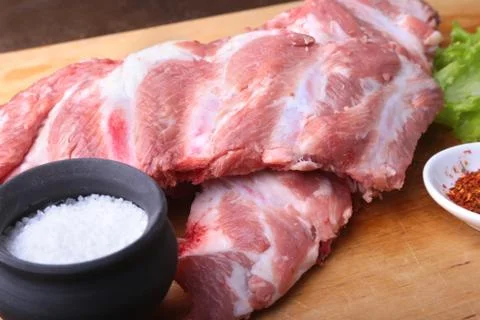 Raw Ribs on a rustic cutting board with salt, pepper and grinder for spices Stock Photos