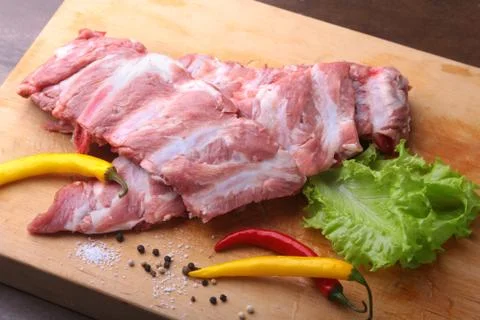 Raw Ribs on a rustic cutting board with salt, pepper and grinder for spices Stock Photos