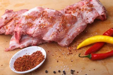 Raw Ribs on a rustic cutting board with salt, pepper and grinder for spices Stock Photos