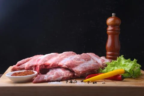 Raw Ribs on a rustic cutting board with salt, pepper and grinder for spices . Stock Photos