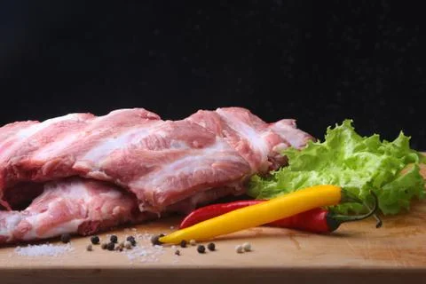 Raw Ribs on a rustic cutting board with salt, pepper and grinder for spices . Stock Photos