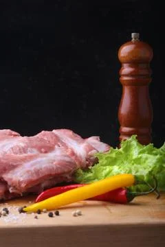 Raw Ribs on a rustic cutting board with salt, pepper and grinder for spices . Stock Photos