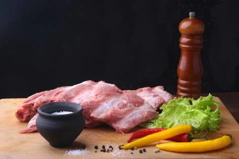 Raw Ribs on a rustic cutting board with salt, pepper and grinder for spices . Stock Photos