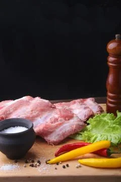 Raw Ribs on a rustic cutting board with salt, pepper and grinder for spices . Stock Photos