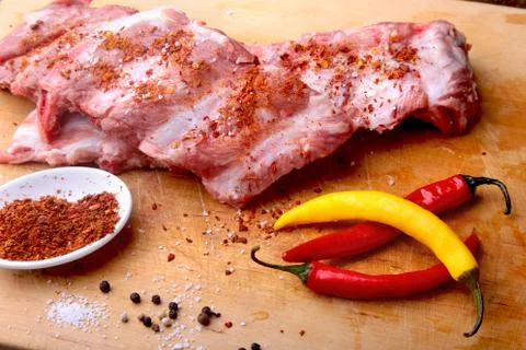 Raw Ribs on a rustic cutting board with salt, pepper and grinder for spices . Stock Photos