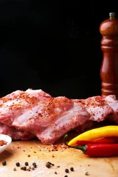 Raw Ribs on a rustic cutting board with salt, pepper and grinder for spices Stock Photos