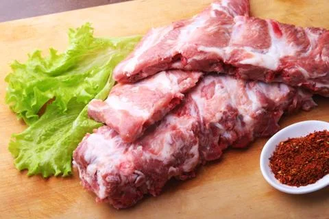 Raw Ribs on a rustic cutting board with salt, pepper and grinder for spices Stock Photos