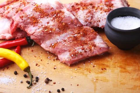Raw Ribs on a rustic cutting board with salt, pepper and grinder for spices Stock Photos