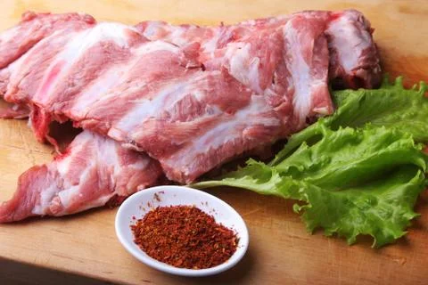 Raw Ribs on a rustic cutting board with salt, pepper and grinder for spices Stock Photos