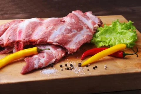 Raw Ribs on a rustic cutting board with salt, pepper and grinder for spices Stock Photos