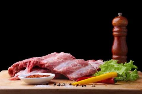 Raw Ribs on a rustic cutting board with salt, pepper and grinder for spices Stock Photos
