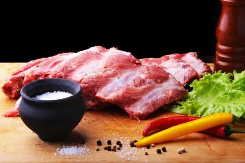 Raw Ribs on a rustic cutting board with salt, pepper and grinder for spices Stock Photos