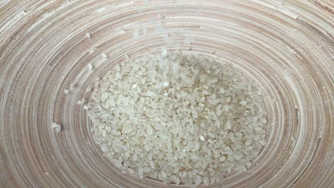 Raw rice grain falling into a bamboo bowl Stock Footage 244385166