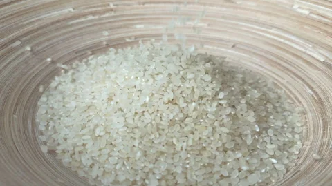 Raw rice grain falling into a bamboo bowl. Stock Footage 244385241