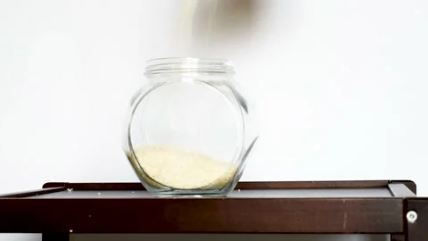 Raw rice grains falling into glass jar. Healthy seeds for cooking Stock Footage 170131168