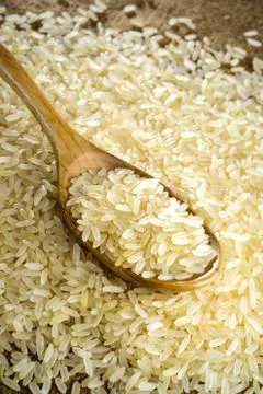 Raw rice in spoon Stock Photos