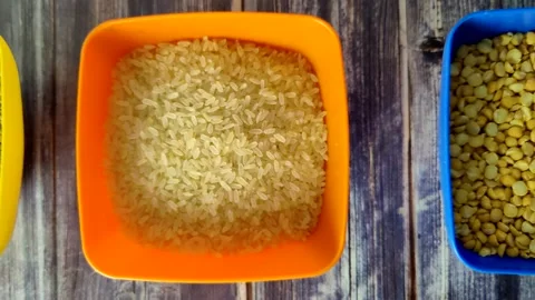 Raw rice, yellow split peas and buckwheat in plastic bowls on a wooden table Stock Footage 231594100