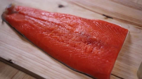 Raw salmon with salt and pepper on wooden table. Video stock 144357515