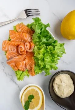 Raw salmon slice or salmon sashimi with green oak salad, lemon and white sauc Stock Photos