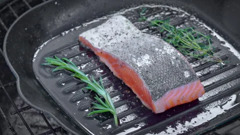 Raw salmon steak is being cooked on a hot cast iron pan Stock Footage 324579008