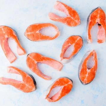 Raw salmon steaks pattern on a blue background top view Stock Photos