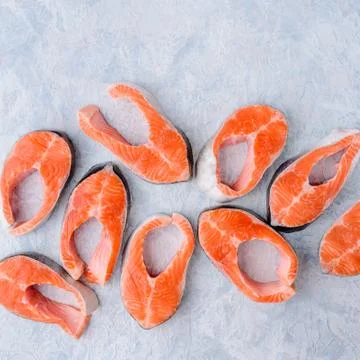 Raw salmon steaks pattern on a blue background top view Stock Photos