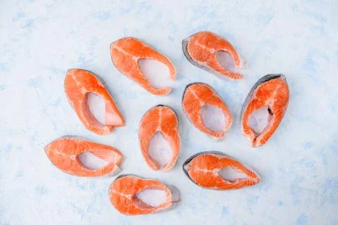 Raw salmon steaks pattern on a blue background top view Stock Photos