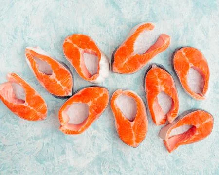 Raw salmon steaks pattern on a blue background top view Stock Photos