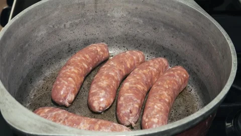 Raw sausage links frying inside a large metal pot 動画素材 339383391