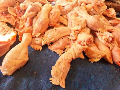 Raw skinned chicken heads piled on dark blue fabric at local butcher counter. Stock Photos