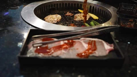 Raw sliced pork with red sauce in a black tray with tongs. In the backgroun.. Stock Footage 336700640