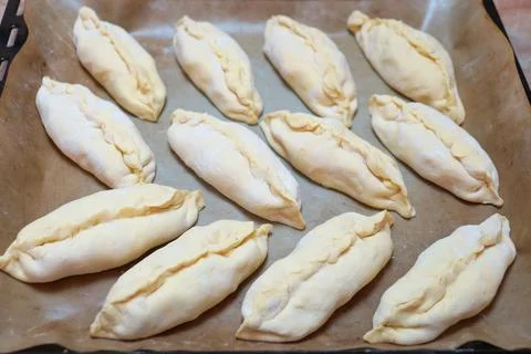 Raw small pies on a baking sheet for food background Stock Photos