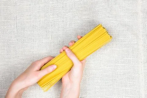 Raw spaghetti in female hands flat lay Stock Photos