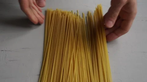 Raw spaghetti in hand on grey background. Slow motion. Video stock 143256815