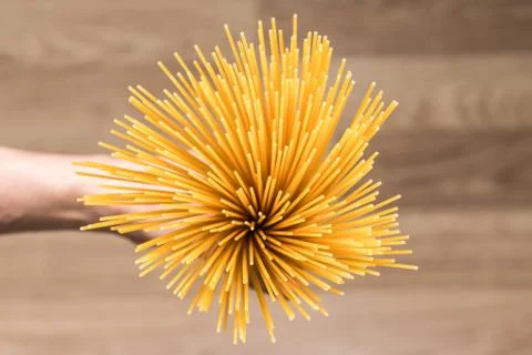 Raw spaghetti in hand, top-down view. Selective focus. Stock Photos