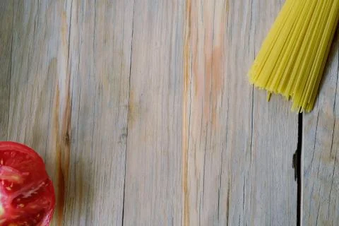 Raw spaghetti pasta and half tomato on wood background Stock Photos