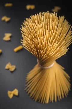 Raw Spaghetti Pasta Bundle and Farfalle on Dark Textured Background Stock Photos