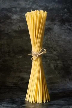 Raw spaghetti stands upright on a dark background Stock Photos