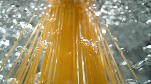 Raw Spaghetti Thrown into Boiling Water Breaks Through the Water's Surface Stock Footage 278831076