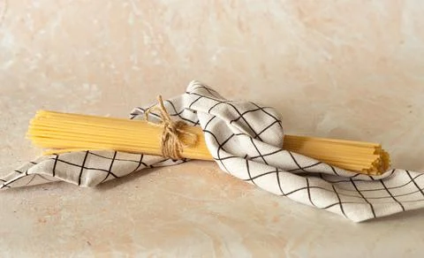 The raw spaghetti is wrapped in a checkered towel Stock Photos
